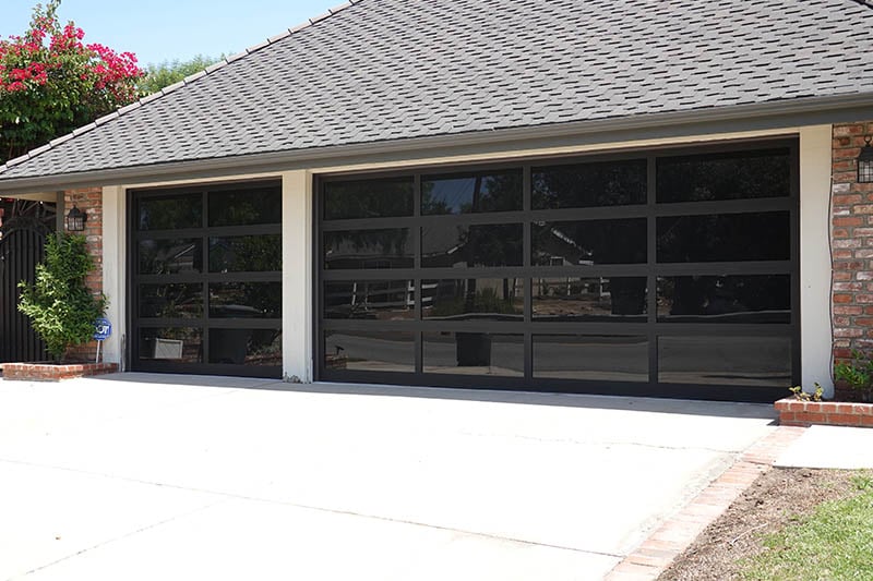 Modern black garage doors on a suburban brick house