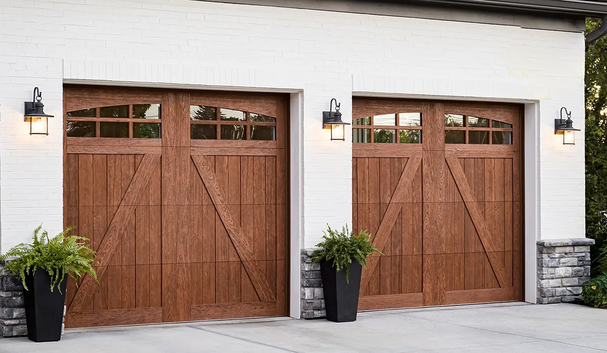 Wooden garage doors with outdoor lighting and potted plants